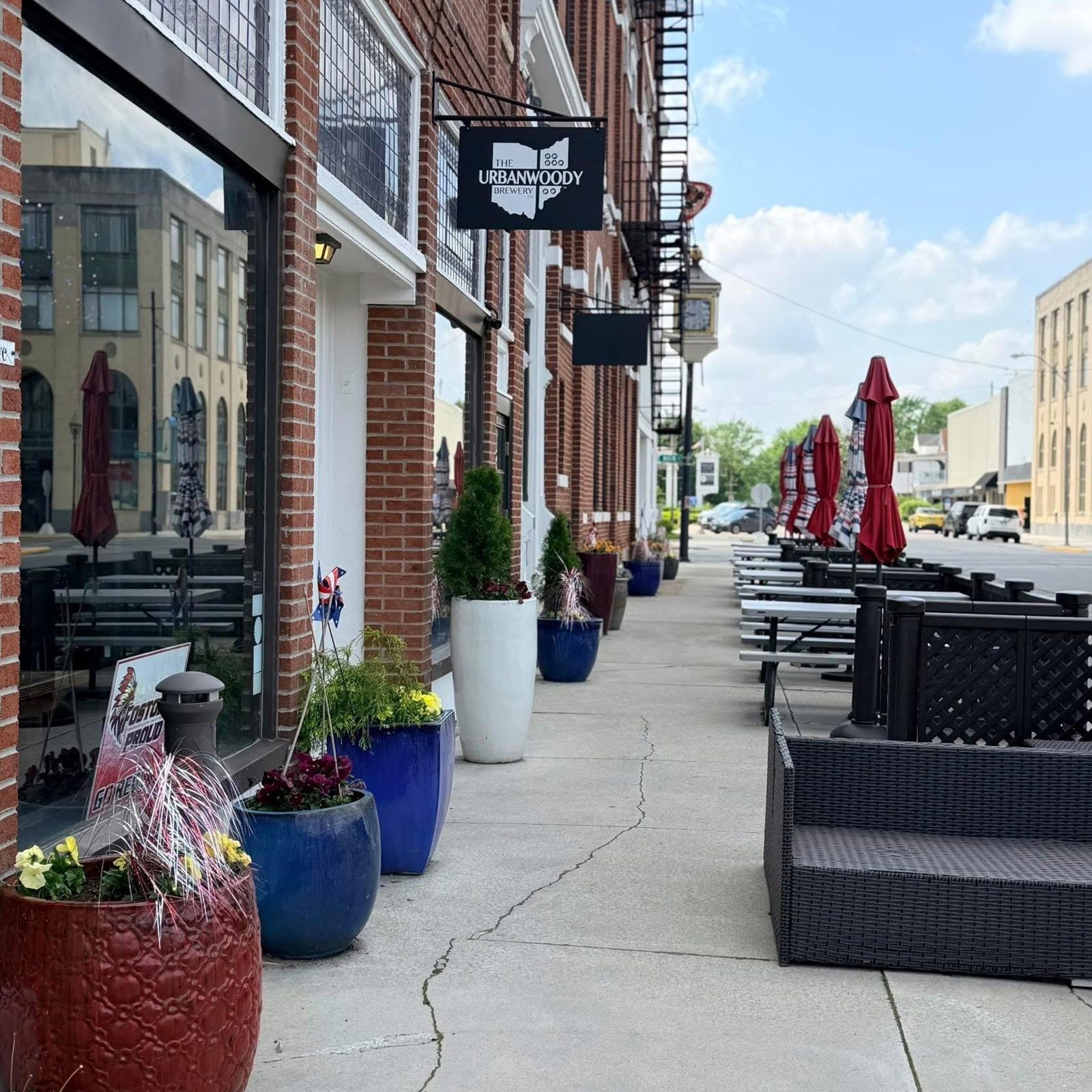 Street view of the red brick UrbanWoody building with outdoor patio seating
